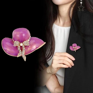 Spilla elegante a cappello viola con fiocco dorato e perla su giacca nera