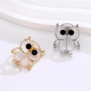 Minimalist owl brooch set in gold and silver finish with black gemstone eyes