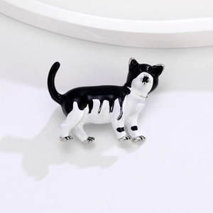 Détail d'une mignonne broche chat en émail noir et blanc avec finitions en métal argenté