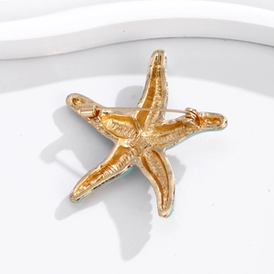 Goldene Seestern-Brosche mit blauer Emaille und Nadelverschluss auf weißem Hintergrund
