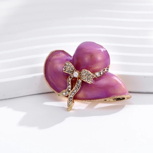 Dettaglio di una spilla a cappello in smalto viola con fiocco di perle e brillantini