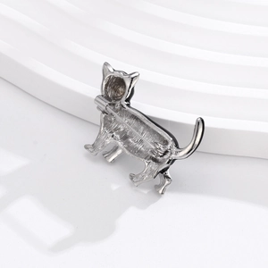 Broche chat en émail argenté avec contours noirs et épingle de fixation sur fond blanc