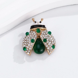 Détail macro d'une broche coccinelle avec pierres vertes en goutte et cristaux fins