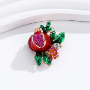Close-up of pomegranate brooch with red enamel and sparkling rhinestones on white base