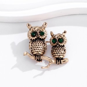 Close-up of vintage owl brooch with green rhinestone eyes on gold-tone branch
