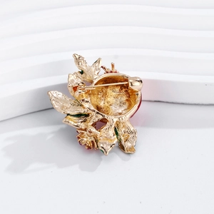 Back view of gold pomegranate brooch featuring pin clasp and red enamel detail