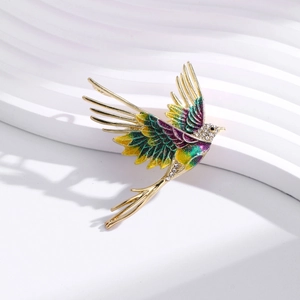Elegant gold-tone bird brooch with gradient enamel wings and crystal inlay on white texture