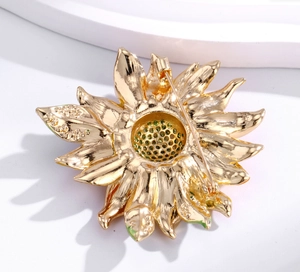 Détails du revers d'une broche tournesol dorée avec fermoir et incrustations de strass verts