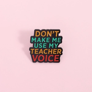 Detail of colorful Teacher Voice enamel pin with vibrant text on a black metal base