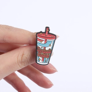Kreative Delulu Juice Emaille-Anstecknadel im rot-blauen Retro-Getränkedesign in der Hand