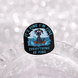 Macro shot of an enamel brooch featuring a dog and 'Everything is fine' quote detail