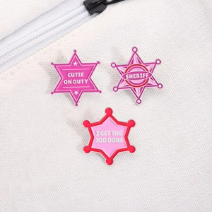 Detailed view of pink enamel sheriff star and cutie on duty badges on a canvas bag