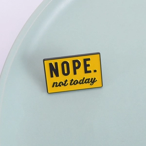 Gros plan sur l'épingle émaillée jaune avec le détail du texte NOPE. not today