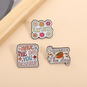 Detail showing three creative enamel pins with inspirational quotes and floral motifs