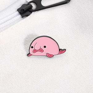 Detailed view of a cute pink blobfish enamel pin attached to a white canvas backpack zipper