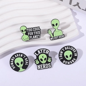 Set of five alien enamel pins with funny slogans on white wavy display tray