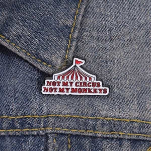 Lustige Zirkuszelt Emaille Brosche mit Spruch auf einem blauen Denim Jackenkragen
