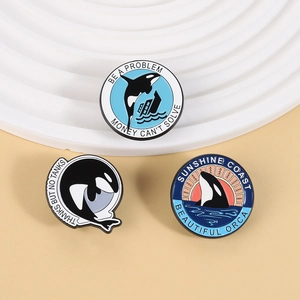 Detail of three orca enamel pins with Thanks But No Tanks text and ocean theme