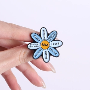 Broche en émail fleur inspirante avec affirmations tenue par les doigts