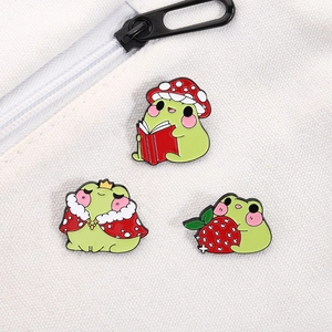 Three cute frog enamel pins with strawberry mushroom and crown on white canvas bag