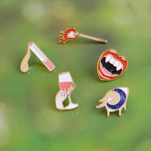 Vibrant enamel pins featuring vampire lips, wine glass, and moon eye on green background