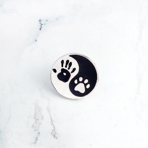 Detailed macro view of enamel brooch featuring yin yang dog paw and handprint design