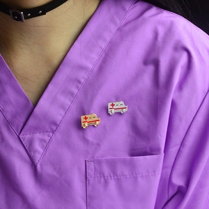 Broches ambulance or et argent avec croix rouge sur blouse médicale violette