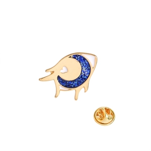 Detailed view of moon eye brooch with sparkling navy pupils and golden metal finish