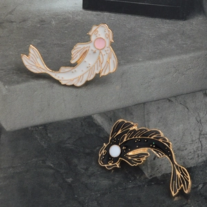 Detailed close-up of pink and black enamel koi fish brooches with golden metal edges
