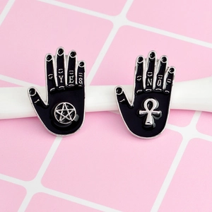 Detail of black enamel witch palm pins with star and ankh symbols on pink background
