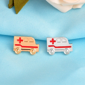 Détail des broches ambulance en or et argent avec croix médicale rouge et émail