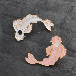 Detail of pink and white enamel koi fish pins with gold edges on stone background