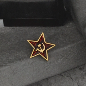 Macro view of Soviet red star pin badge with golden hammer and sickle emblem