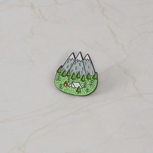 Outdoor camping enamel pin featuring snow-capped mountains and forest landscape design