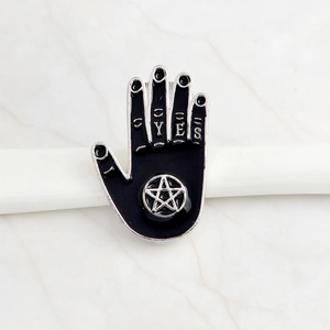 Macro detail of black enamel witch hand pin with YES text and pentagram star symbol