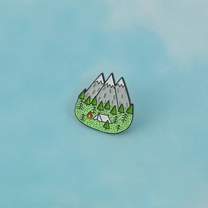 Outdoor camping enamel pin featuring snow-capped mountains, forest, tent and campfire design