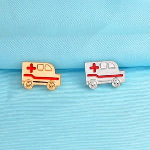 Vue détaillée des broches ambulance en métal doré et argenté avec logo croix rouge