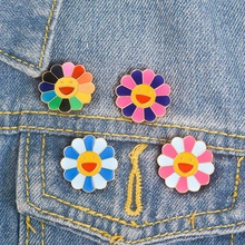 Detail view of four colorful enamel smiley flower pins on a blue denim jacket pocket