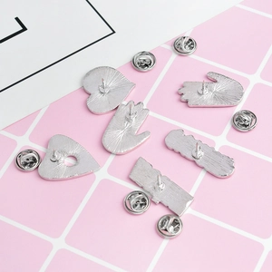 Detail view of silver alloy brooch backs with butterfly clutch pins on a grid background