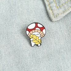 Detail of cute mushroom enamel pin with yellow leaf on blue denim jacket fabric