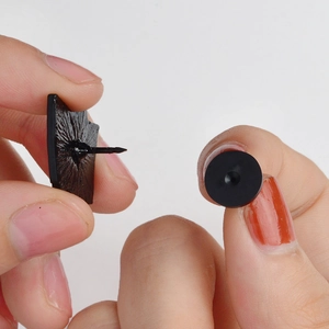 Dettaglio di una spilla in smalto nero con retro strutturato e chiusura in gomma nera