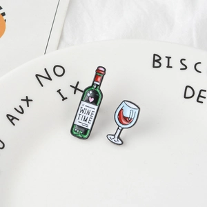 Set di spille smaltate a forma di bottiglia e bicchiere di vino rosso su piatto