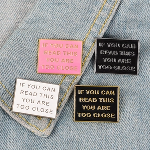 Set of four colorful enamel warning pins on denim fabric with bold warning text