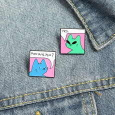 Pop art style enamel cat pins with conversation bubbles pinned on blue denim jacket pocket