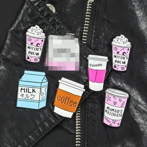Cartoon coffee and milk enamel pins displayed on a black leather jacket texture