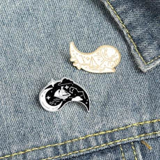 Detail of day and night enamel pins with sun, moon and sailboat on denim jacket