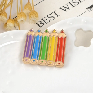 Broche crayon en émail arc-en-ciel avec bordure dorée sur plateau décoratif