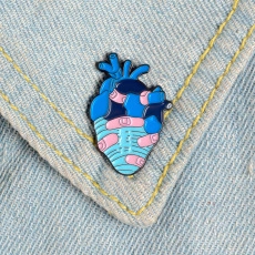 Detail of anatomical heart enamel pin in pink and blue pinned on denim fabric