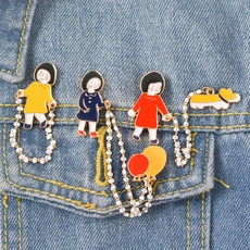 Détail de broches en émail dessin animé avec chaînes de perles sur tissu en denim