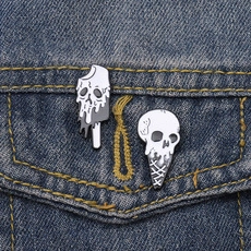 Details von kreativen Totenkopf-Eis-Emaille-Pins an einer blauen Jeansjackentasche